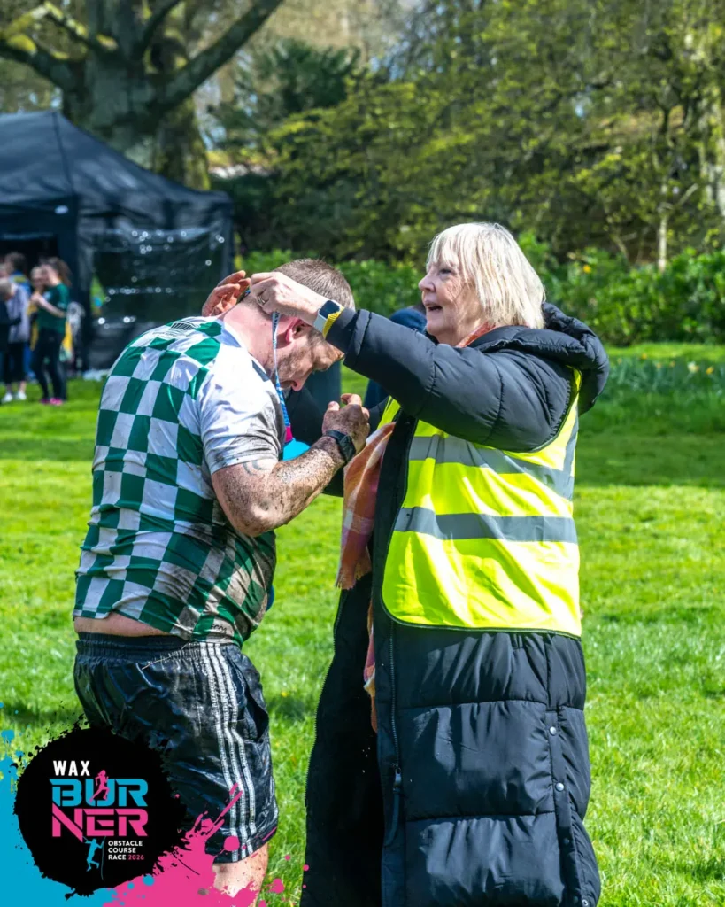 A WAX volunteer handing a medal to a WAX Burner participant