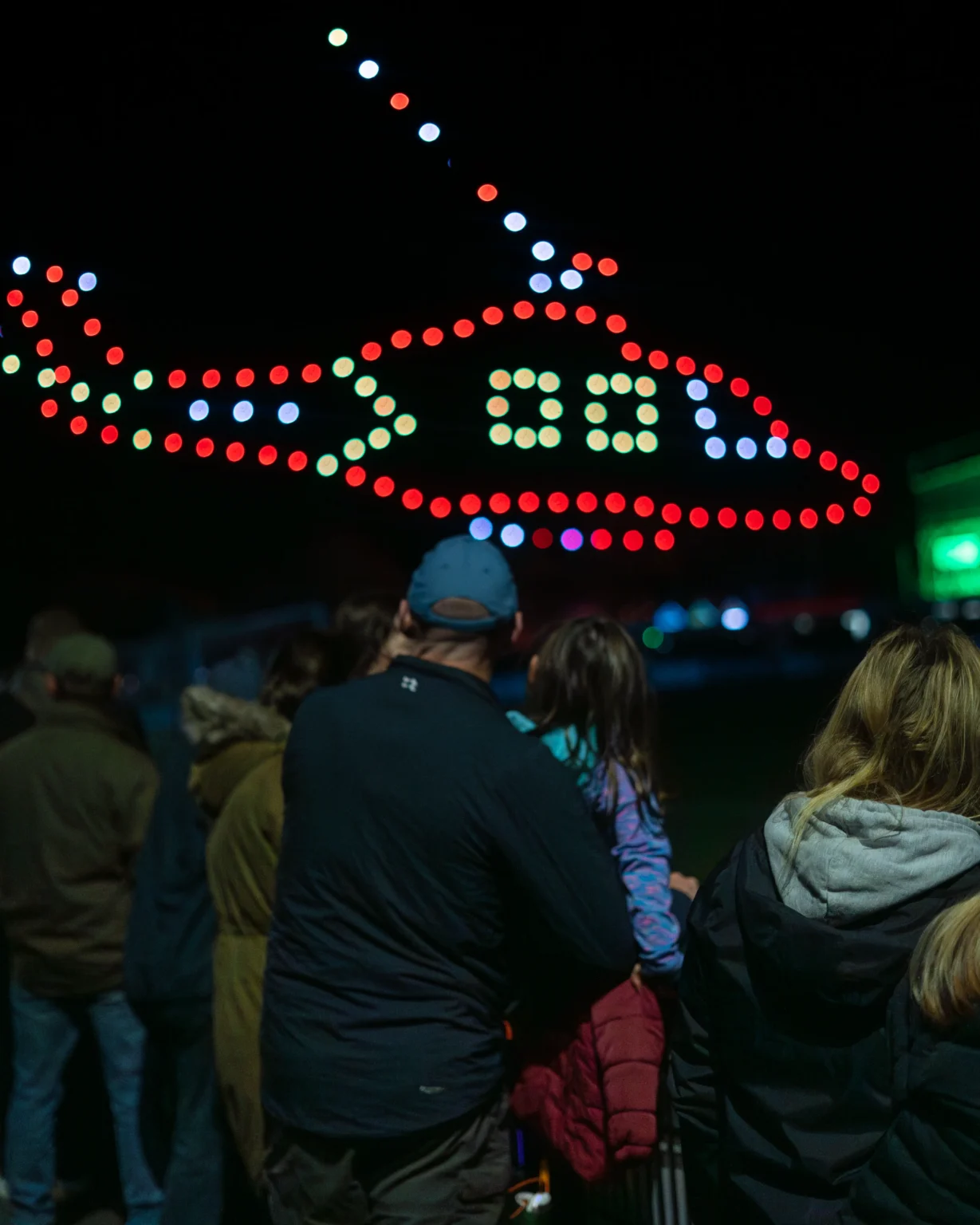 Families watching a WAX drone show at night
